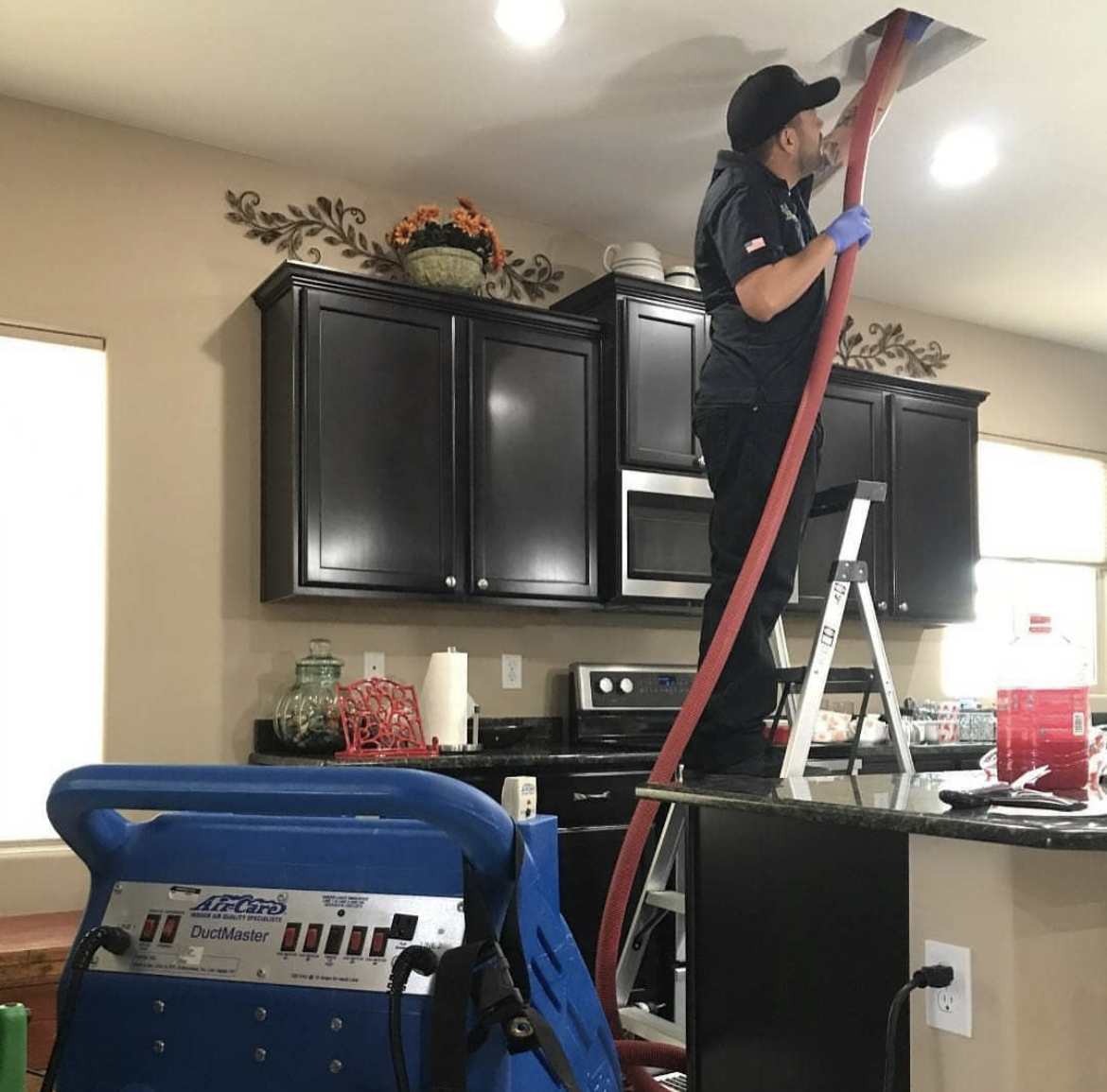 CleanFlow Pros technician cleaning an Arlington home's supply vent using negative-air duct cleaning equipment