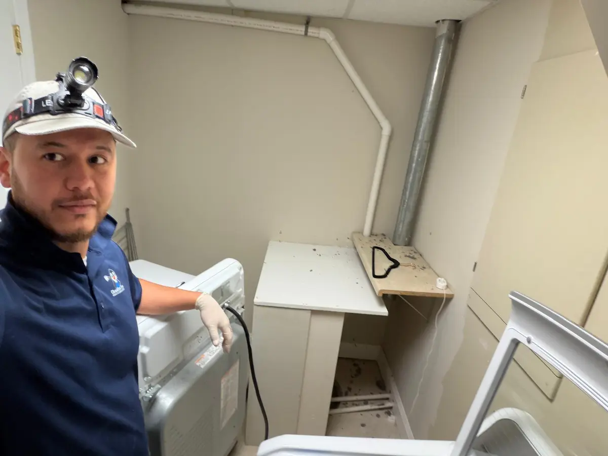 CleanFlow Pros technician inspecting the vent stub behind a pulled-out dryer in a laundry closet